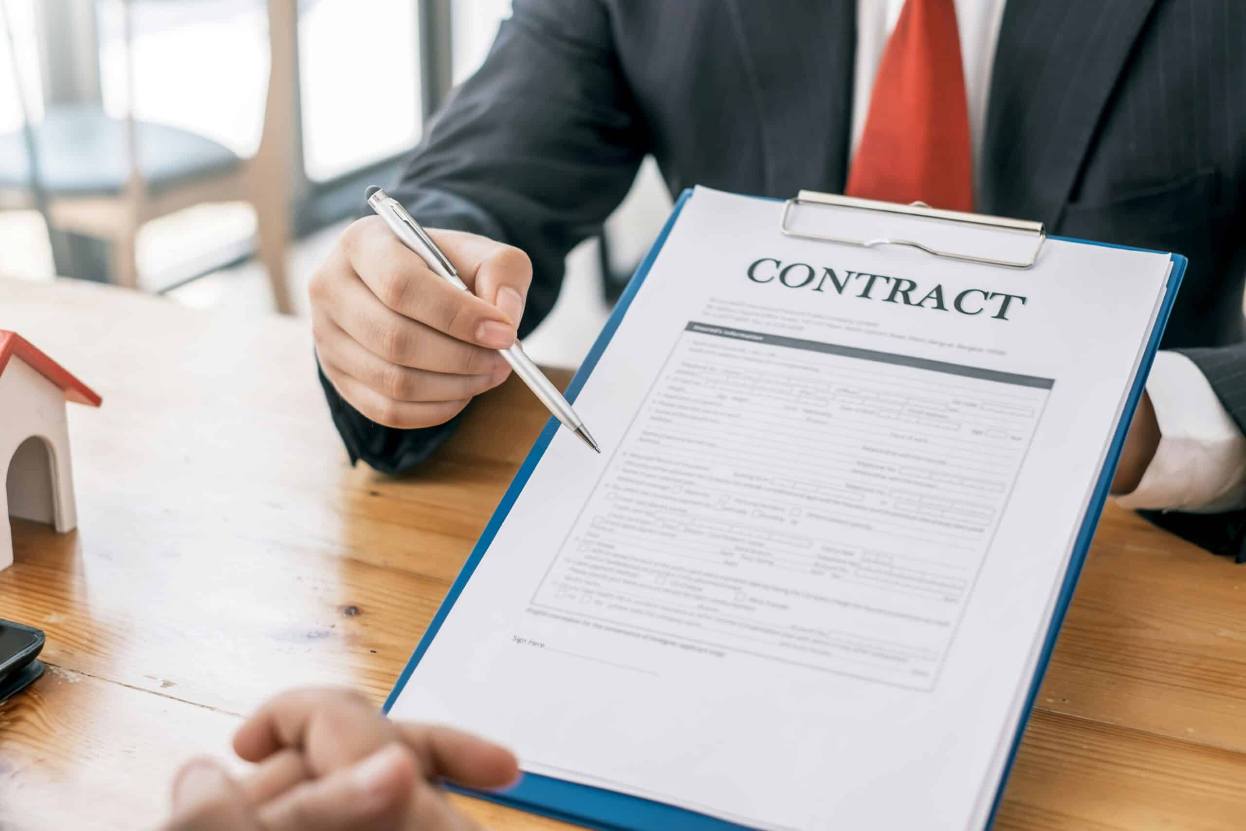 A man in a suit pointing to where to sign in a contract